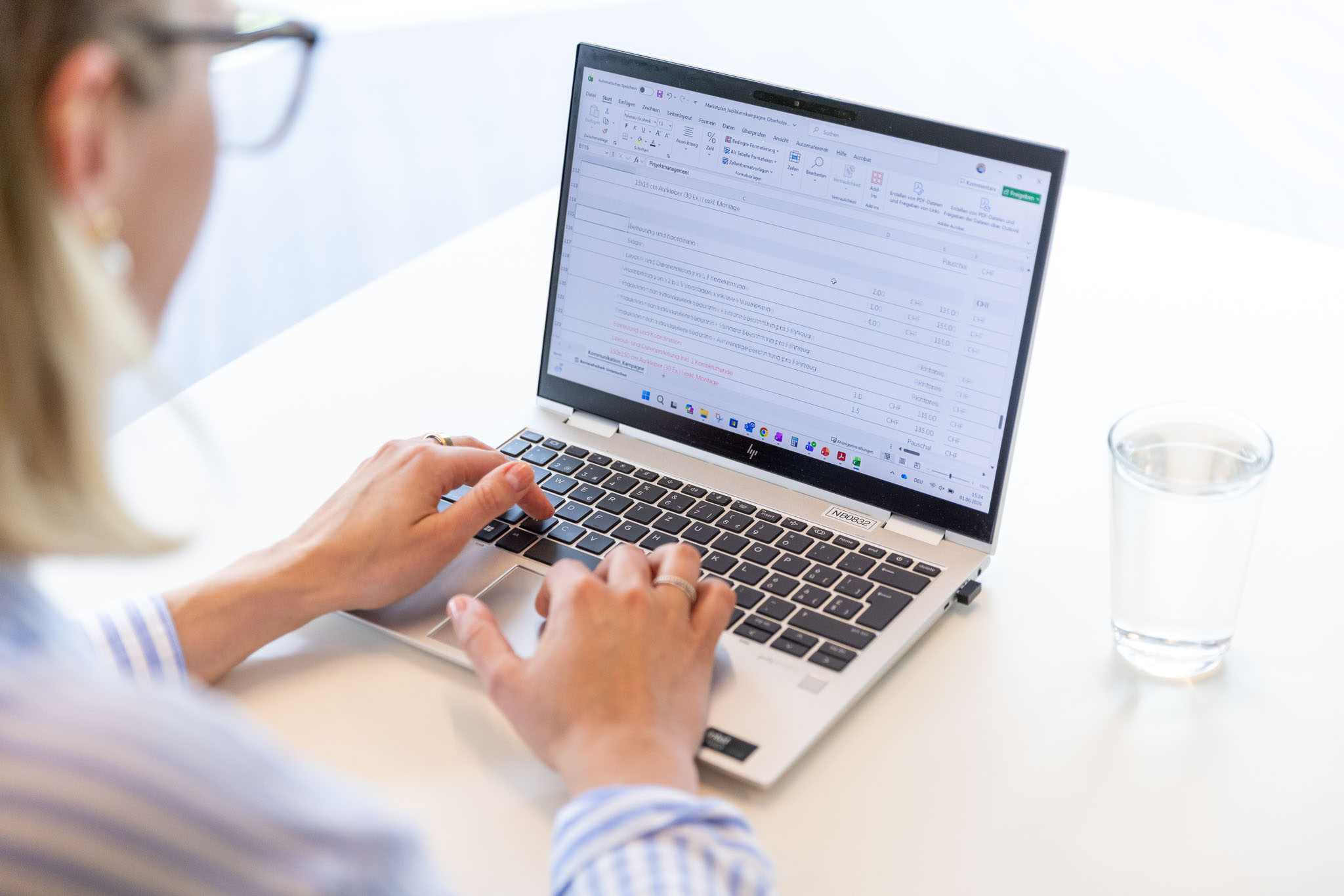 Offline und Online Marketing Person arbeitet an einem Laptop mit geöffneter Tabellenkalkulation.